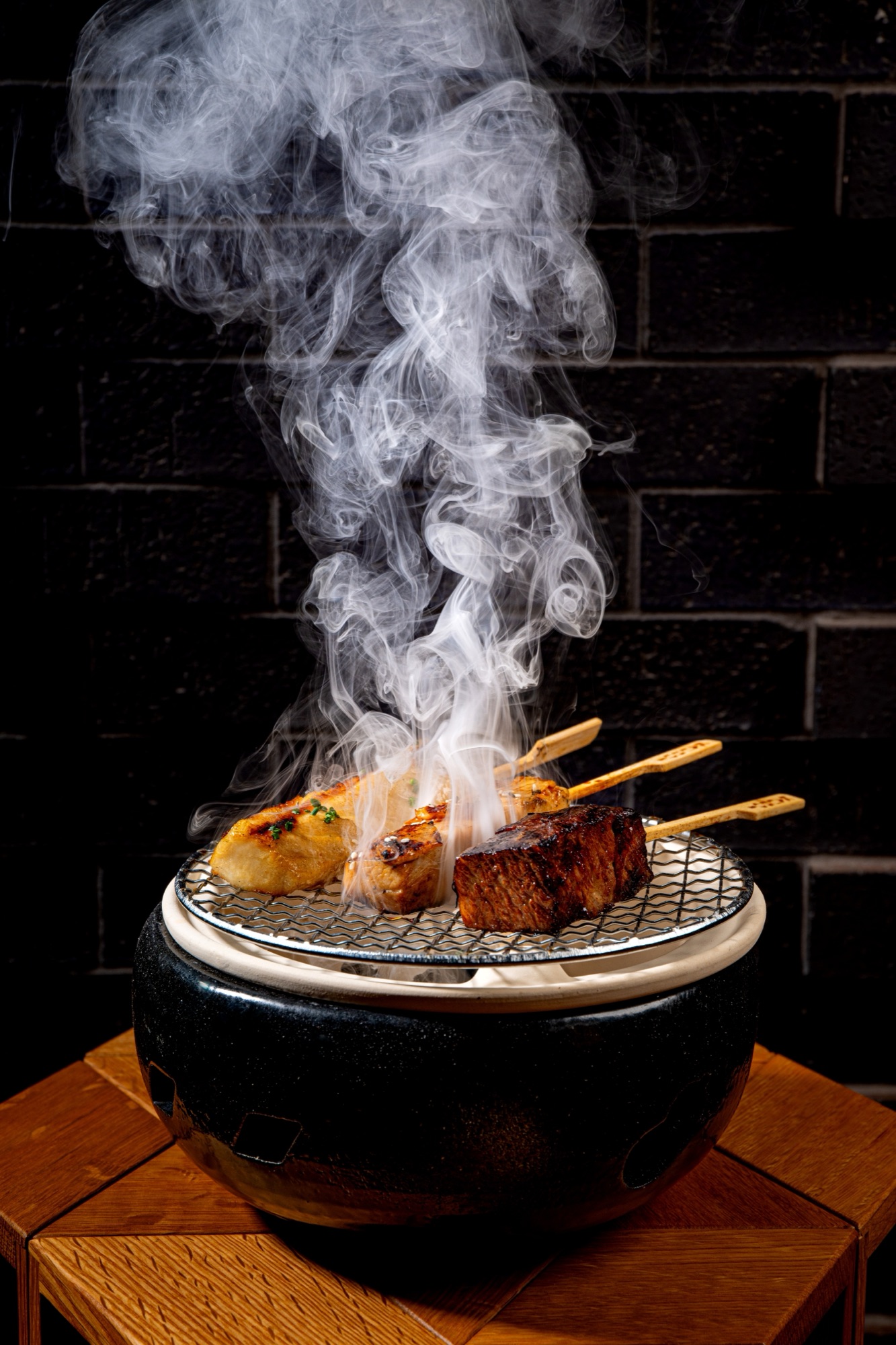 Yakitori skewers smoking on a tabletop charcoal grill